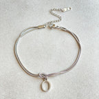 Silver bracelet with a small round pendant on a light gray background
