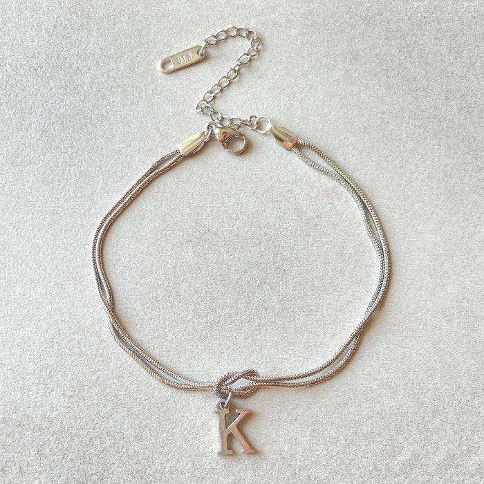 Silver bracelet with a 'K' charm on a light gray background