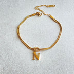 Gold bracelet with a 'N' charm on a light gray background