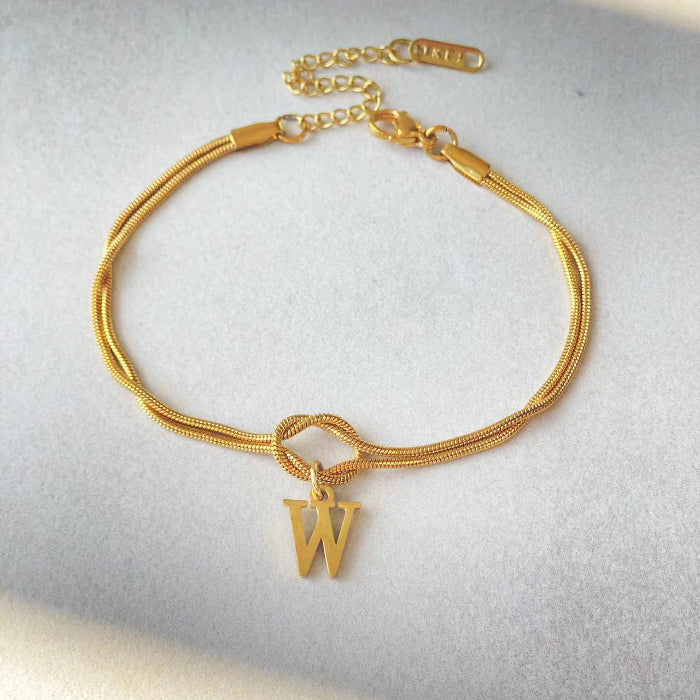 Gold bracelet with a letter 'W' charm on a light gray background
