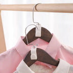 6 Hanger Connection Hooks connecting two wooden hangers holding pink and white shirts in a closeup view.