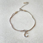 Silver bracelet with a moon charm on a light gray background