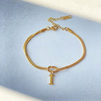 Gold bracelet with a letter 'I' charm on a light blue background