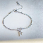 Silver bracelet with a knot and letter 'F' charm on a light gray background