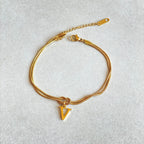 Gold bracelet with a letter 'V' charm on a light gray background