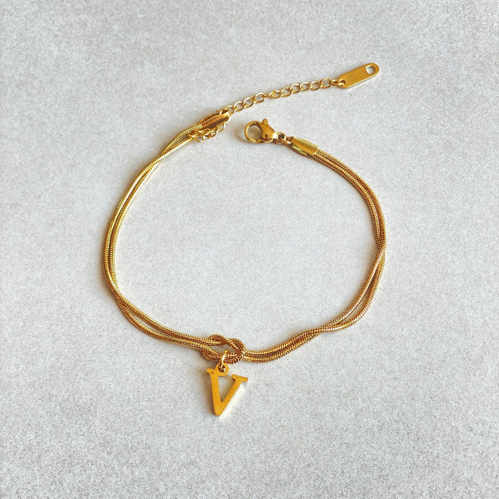 Gold bracelet with a letter 'V' charm on a light gray background