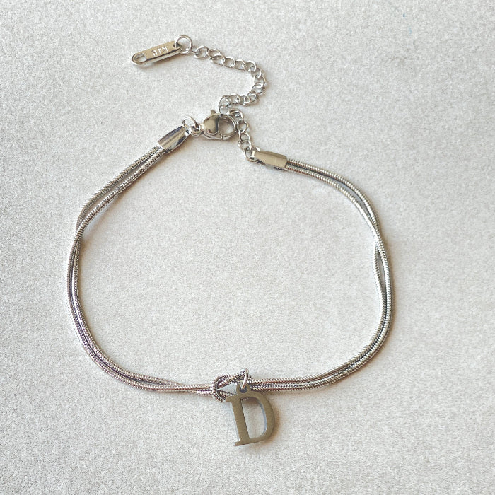 Silver bracelet with a 'D' charm on a light gray background