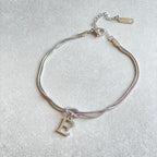 Silver bracelet with a letter 'E' charm on a light gray background