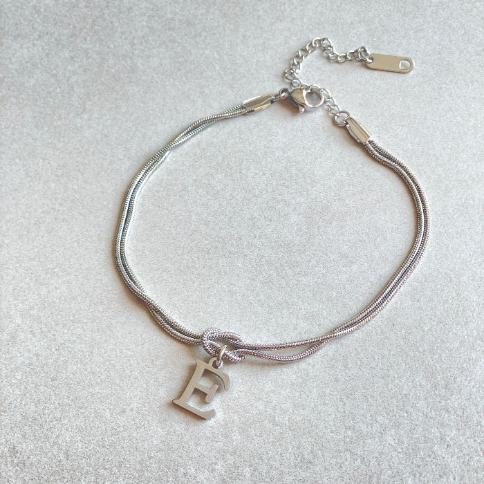 Silver bracelet with a letter 'E' charm on a light gray background