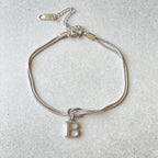 Silver bracelet with a letter 'B' charm on a light gray background