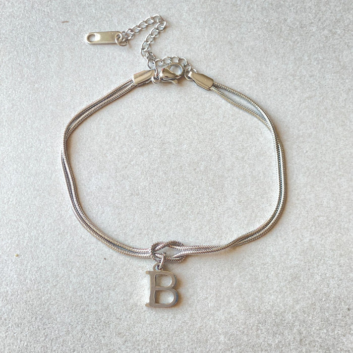 Silver bracelet with a letter 'B' charm on a light gray background