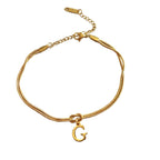 Gold bracelet with a 'G' charm on a white background