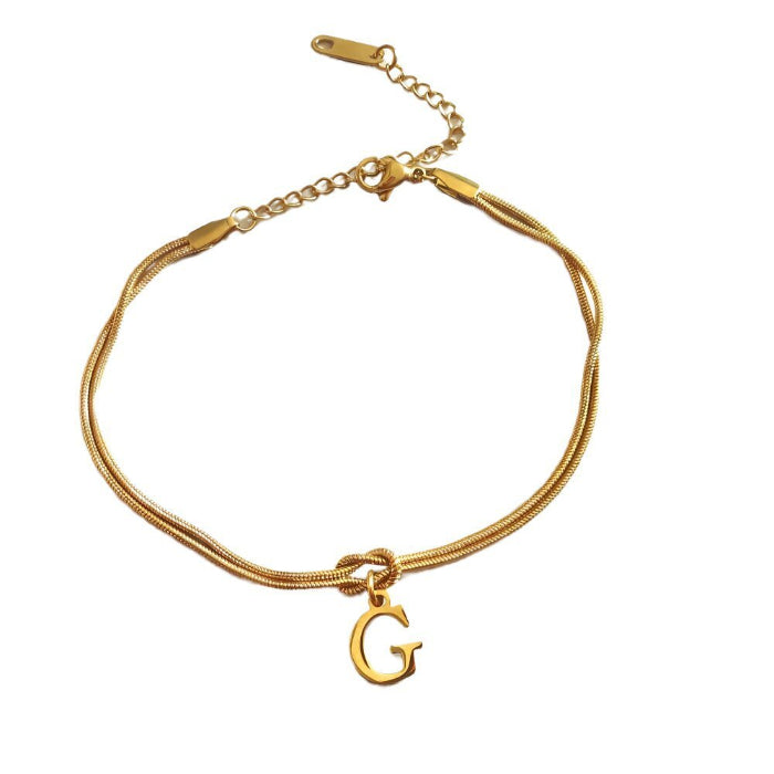 Gold bracelet with a 'G' charm on a white background