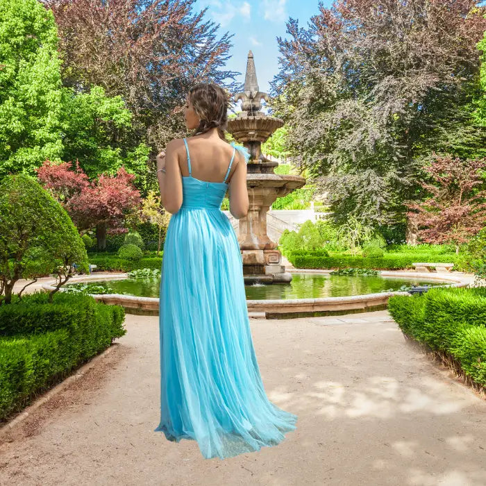 Back view of a model in a flowy light blue prom dress showing delicate spaghetti straps and the long, sheer skirt fabric