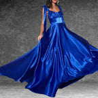 Model showcasing a stunning royal blue satin prom dress indoors. The long, flowing skirt and tie-shoulders create elegance.