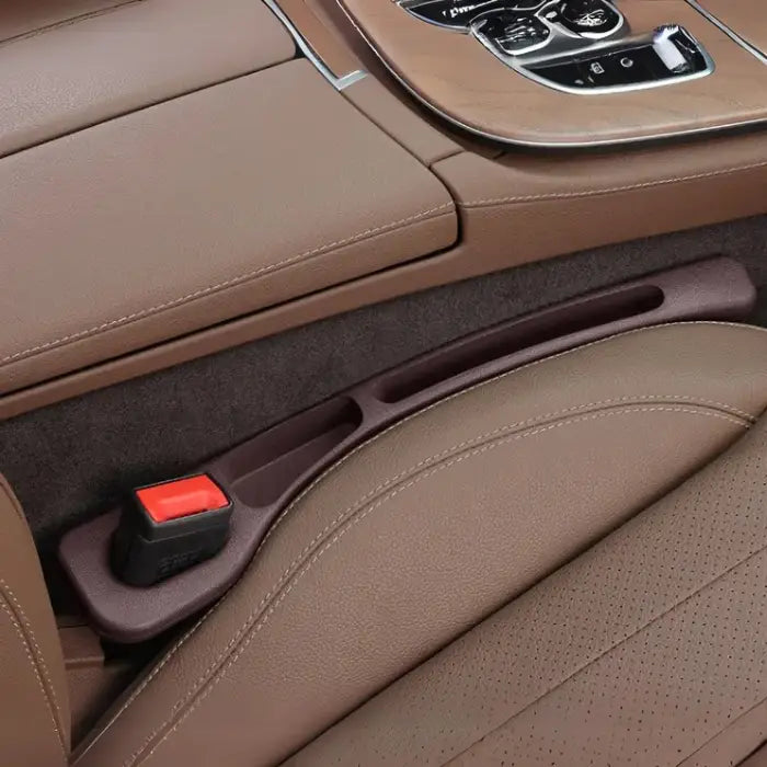 Brown car seat gap filler installed in luxury vehicle with brown leather upholstery