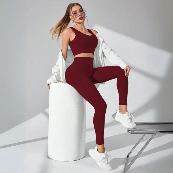 Athletic two-piece set in burgundy ribbed fabric with white leg warmers and chunky sneakers, studio photography with dramatic shadows