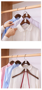 White shirt on a hanger with hands adjusting it, surrounded by other shirts.