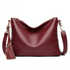 Close-up of wine red cowhide leather handbag, emphasizing material quality.