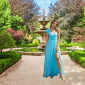 Model confidently displays the high slit on her gorgeous flowy light blue prom dress while posing in a scenic garden setting