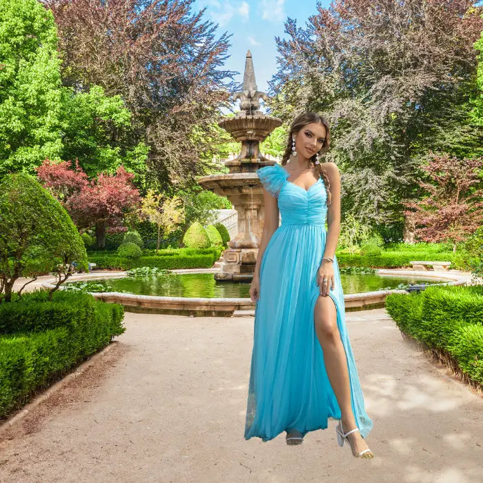 Model confidently displays the high slit on her gorgeous flowy light blue prom dress while posing in a scenic garden setting