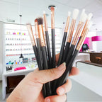 Professional makeup brushes with black handles and copper ferrules displayed in a modern salon setting with nail polish collections in the background.
