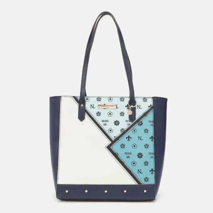 Navy and white tote bag with geometric pattern, floral designs, and gold hardware accents