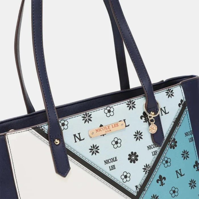 Close-up of handbag logo plate and patterned fabric detail with floral and monogram designs