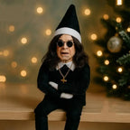 Ozzy Osborne Elf on the shelf doll in black outfit with sunglasses and Christmas lights in background