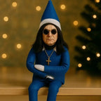 Ozzy Osborne Elf on the shelf doll in blue suit and cross necklace sitting near holiday tree