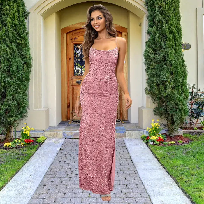 Elegant pink sequin prom dress with body-hugging silhouette, straight neckline and thin spaghetti straps, photographed against stone balustrade