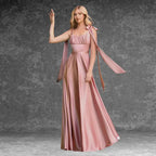 Model wearing a beautiful pink satin prom dress outdoors. Features delicate tie straps, ruched bust, and a graceful A-line skirt.