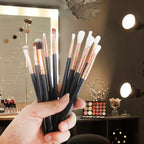 Professional makeup brushes with black handles and rose gold ferrules held at a makeup station with palette, vanity lighting and decorative elements.