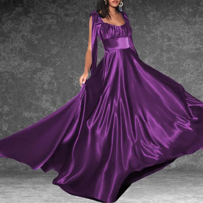 Elegant purple satin prom dress displayed on a mannequin. Features tie-shoulders, ruched bust, and a long flowing skirt.