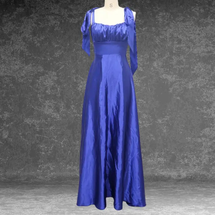 Front view of a royal blue satin prom dress on a dress form. Highlights the square neckline, empire waist, and tie details.