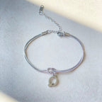 Silver bracelet with a letter 'Q' charm on a light gray background