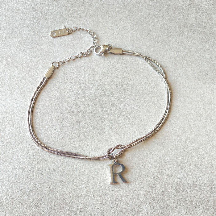 Silver bracelet with a letter 'R' charm on a light gray background