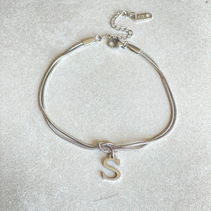 Silver bracelet with a letter 'S' charm on a light gray background