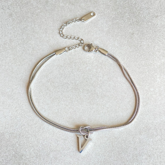 Silver bracelet with a triangle charm letter v on a light gray background