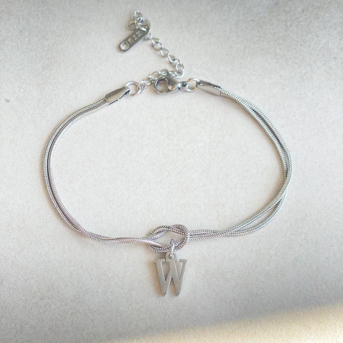 Silver bracelet with a letter 'W' charm on a light gray background