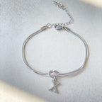 Silver bracelet with a letter 'X' charm on a light gray background