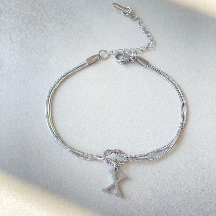Silver bracelet with a letter 'X' charm on a light gray background
