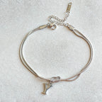 Silver bracelet with a letter charm on a light gray background Letter Y