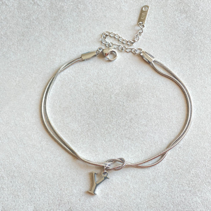 Silver bracelet with a letter charm on a light gray background Letter Y