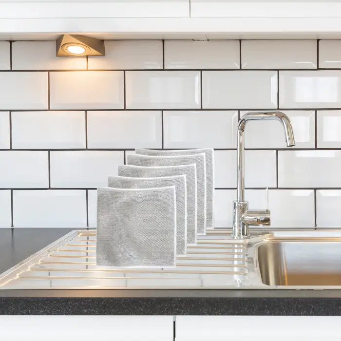 set of 5 silver mesh dish cloths neatly arranged on a kitchen sink, showcasing their durable and reusable design for effective cleaning.