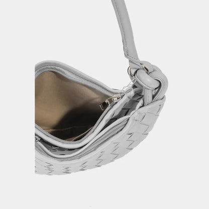 Silver white handbag interior with gold lining, visible zipper, and knotted strap detail