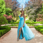 Posing near a fountain, a model wears an elegant flowy light blue prom dress with a sweetheart neckline. Perfect formalwear