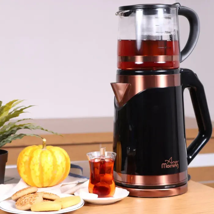 Electric tea maker with autumn decor including pumpkin, cookies, and served tea in traditional glass.