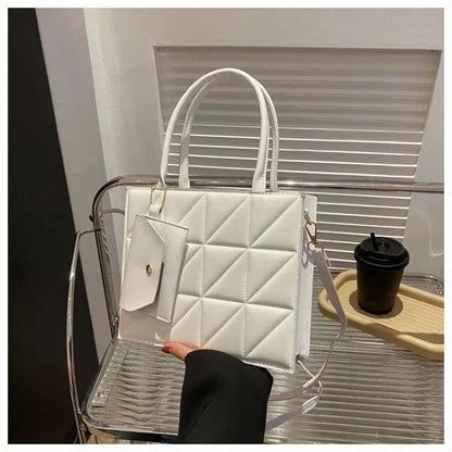 White quilted handbag with geometric pattern and gold hardware, displayed on a clear acrylic chair next to a coffee cup