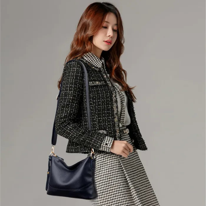 Fashionable woman in tweed jacket carrying a sleek black leather shoulder bag.